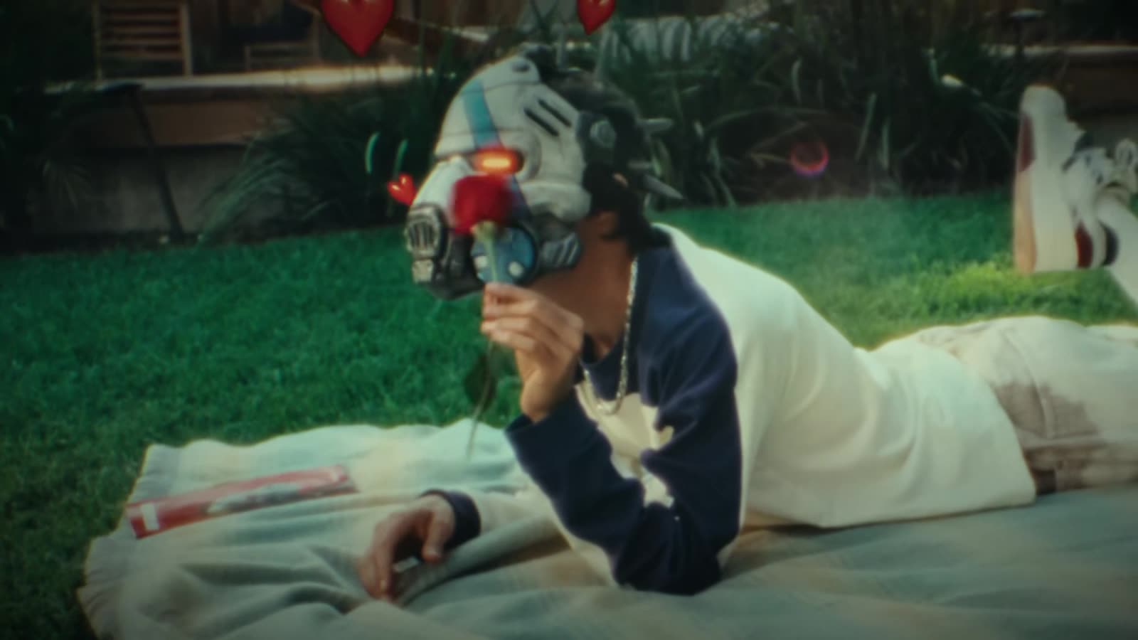 Masked player lying on a lawn with a handheld console
