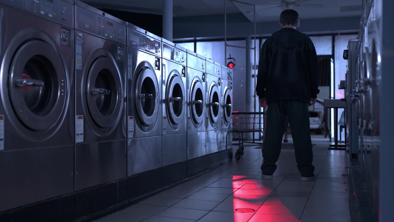 Man walking through a laundromat toward a red doorway