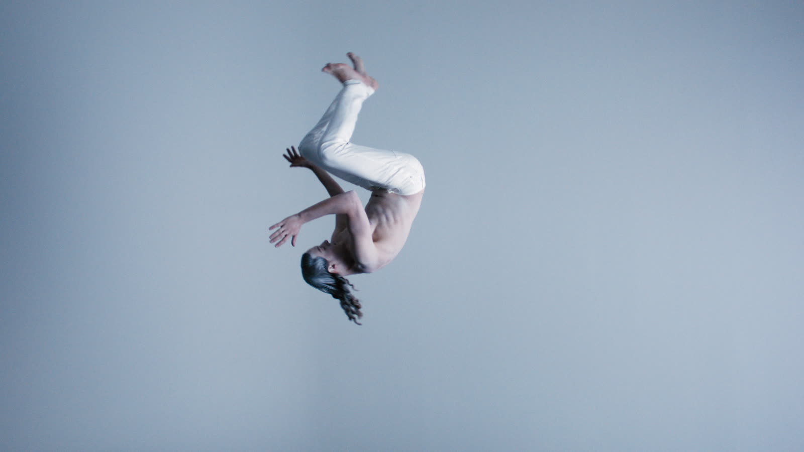 Performer suspended mid-air in a white void